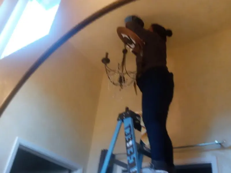 Electrician installing a chandelier in a Lowell residence
